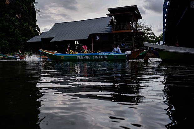 Wisatawan berwisata menggunakan perahu listrik di kawasan Karst Rammang-rammang.