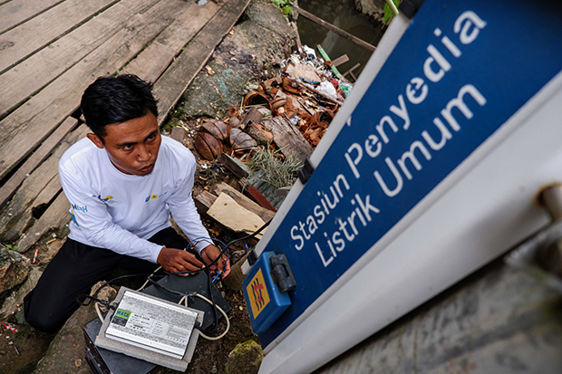 Operator perahu listrik Sunardi melakukan pengisian baterai di Stasiun Penyedia Listrik Umum.