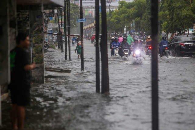 Sejumlah kendaraan menerobos banjir yang menutupi jalan protokol pusat Kota Makassar, (13/2/2023).