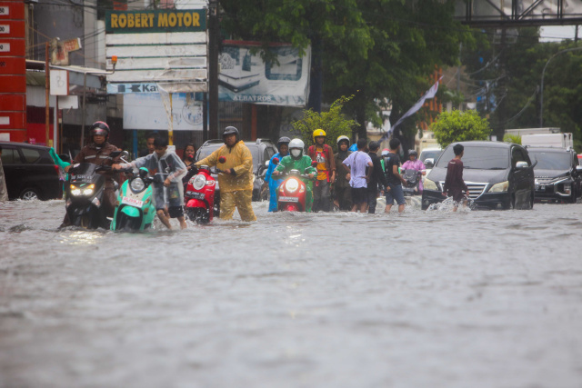 Sejumlah kendaraan menerobos banjir yang menutupi jalan protokol pusat Kota Makassar, (13/2/2023).