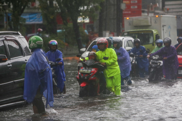 Sejumlah kendaraan menerobos banjir yang menutupi jalan protokol pusat Kota Makassar, (13/2/2023).