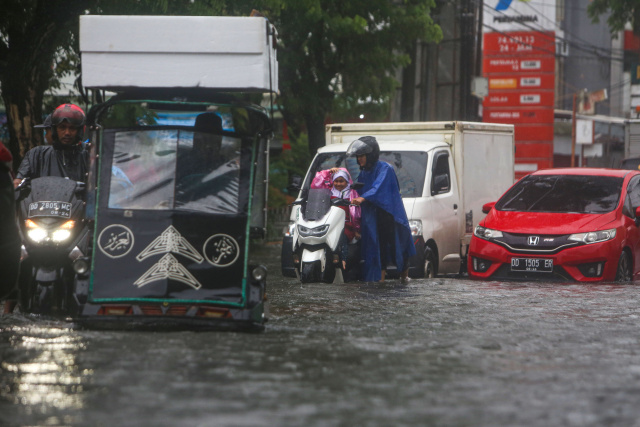 Sejumlah kendaraan menerobos banjir yang menutupi jalan protokol pusat Kota Makassar, (13/2/2023).