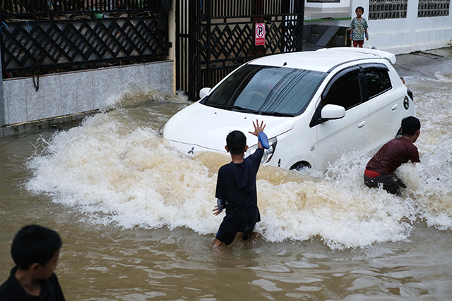 Sejumlah anak bermain di tengah banjir Jalan Nipa-nipa, Makassar.