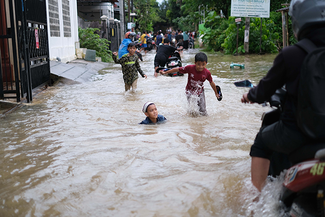 Sejumlah anak bermain di tengah banjir Jalan Nipa-nipa, Makassar.