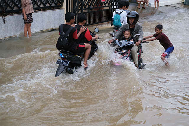 Sejumlah anak bermain di tengah banjir Jalan Nipa-nipa, Makassar.