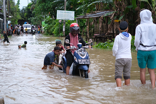 Sejumlah anak bermain di tengah banjir Jalan Nipa-nipa, Makassar.