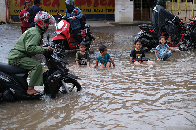 Sejumlah anak bermain di tengah banjir Jalan Nipa-nipa, Makassar.