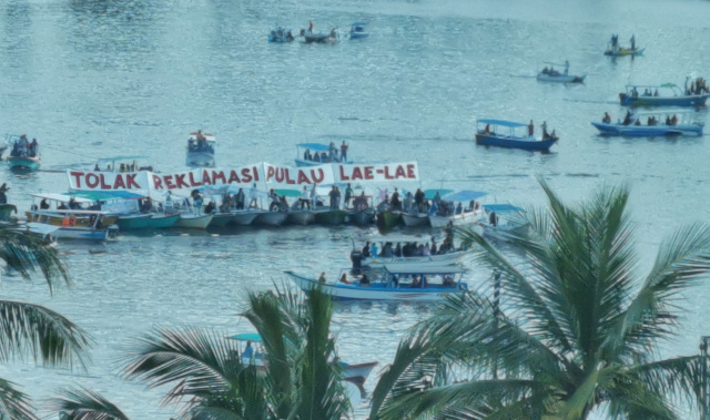 Warga Pulau Lae-Lae menggelar aksi dengan membentangkan spanduk  menolak reklamasi di perairan Pantai Losari.