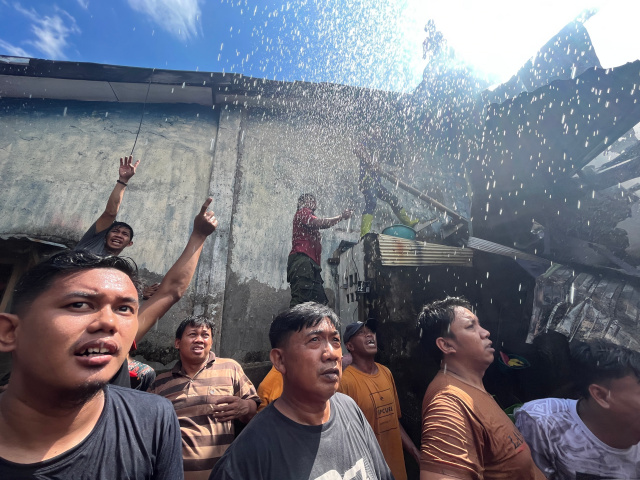 Petugas pemadam kebakaran dibantu warga berusaha memadamkan api yang melalap pemukiman di Jalan Dato Ribandang, Kelurahan Kalukuang, Makassar, Kamis (16/03/2023).