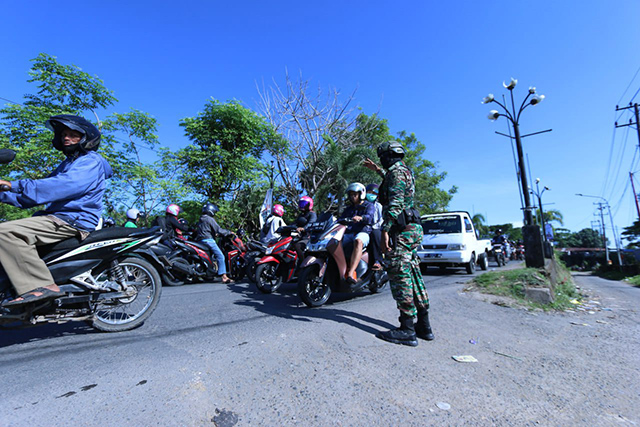 Prajurit TNI Serka Takbir mengatur arus lalu lintas untuk mengurai kemacetan di Jembatan Barombong.
