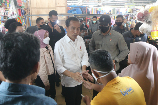 Presiden Jokowi membagikan baju kaos ke pedagang dan pengunjung Pasar Tramo Kabupaten Maros, Sulawesi Selatan, Rabu (29/3/2023).