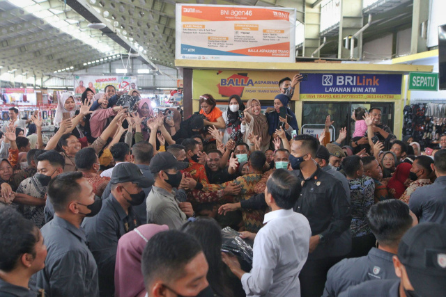 Presiden Jokowi membagikan baju kaos ke pedagang dan pengunjung Pasar Tramo Kabupaten Maros, Sulawesi Selatan, Rabu (29/3/2023).