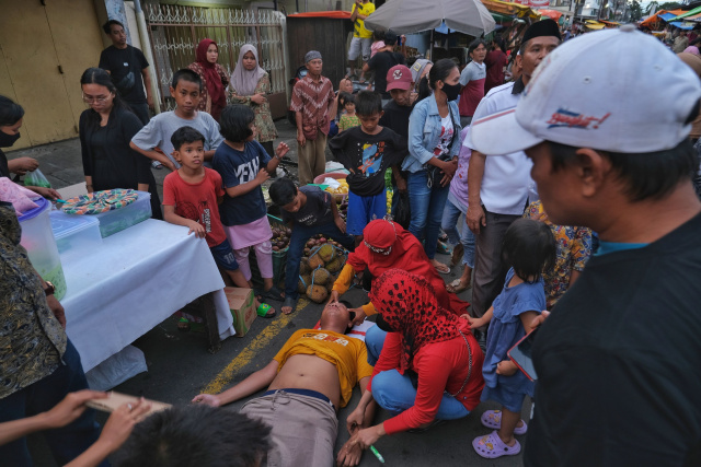 Seorang warga pingsan saat ikut berdesak-desakan menanti kedatangan Presiden Joko Widodo di Pasar Terong, Makassar, Sulawesi Selatan, Rabu (29/3/2023).