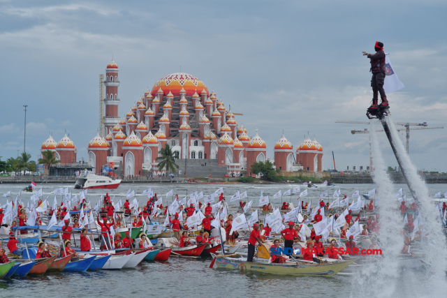 Seratus perahu ketinting berjajar membentuk formasi segitiga di sepanjang Pantai Losari.