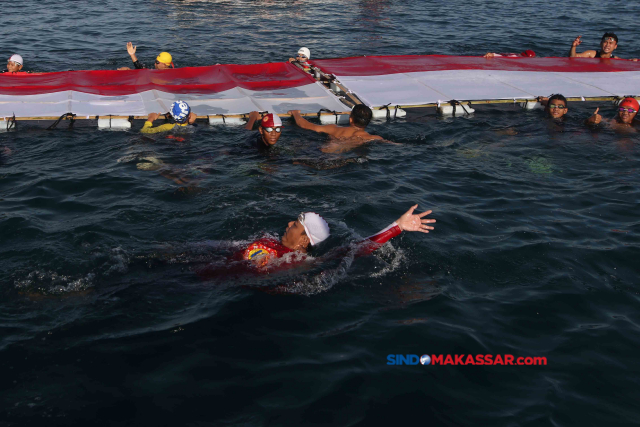 Sejumlah perenang mengibarkan Bendera Merah Putih sepanjang 78 meter ke tengah pesisir laut Kota Makassar, Sulawesi Selatan, Sabtu (12/8/2023).