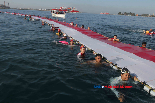 Sejumlah perenang mengibarkan Bendera Merah Putih sepanjang 78 meter ke tengah pesisir laut Kota Makassar, Sulawesi Selatan, Sabtu (12/8/2023).