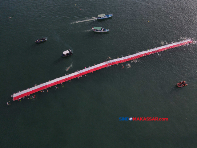 Sejumlah perenang mengibarkan Bendera Merah Putih sepanjang 78 meter ke tengah pesisir laut Kota Makassar, Sulawesi Selatan, Sabtu (12/8/2023).