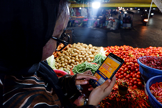 Pedagang melakukan pembelian emas lewat online melalui website resmi www.logammulia.com di Pasar Terong, Makassar, Selasa (12/9/2023).