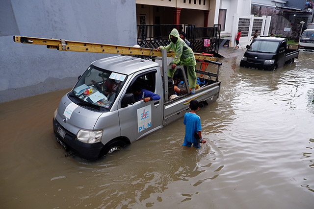 Pekerja PLN melewati banjir di Kelurahan Manggala, Makassar, (28/12/2022).