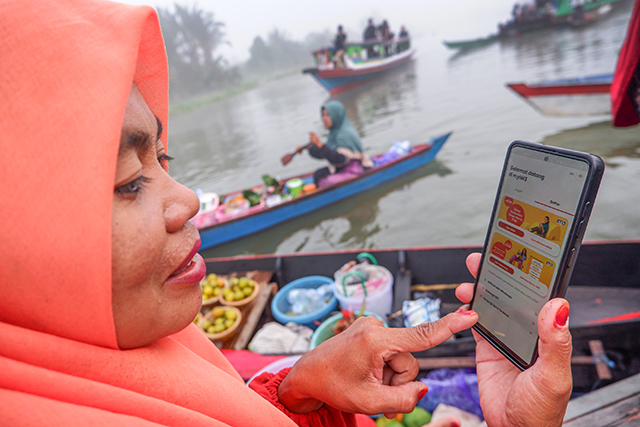 Seorang pedagang pasar terapung mengakses myIM3 dari Indosat di Pasar Terapung, Kabupaten Banjarmasin, Kalimantan Selatan, Rabu (1/11/2023).