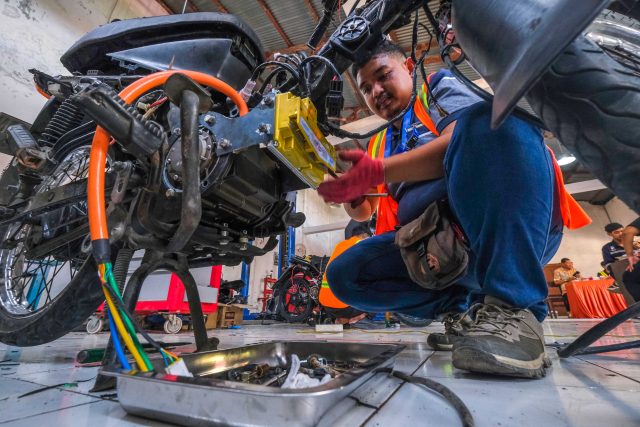 Sejumlah peserta teknisi dan mekanik memasang komponen motor listrik ke badan sepeda motor berbasis BBM di SMK Negeri 10 Makassar, (23/11/2023). 