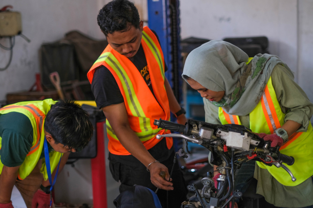 Sejumlah peserta teknisi dan mekanik memasang komponen motor listrik ke badan sepeda motor berbasis BBM di SMK Negeri 10 Makassar, (23/11/2023). 