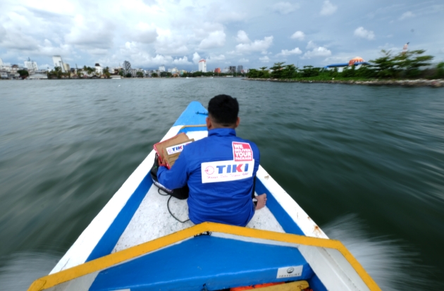 Kurir TIKI tengah mengantarkan paket pada warga dengan menumpangi perahu di Pulau Barrang Lompo, Kota Makassar, (7/1/2024). Foto-foto/Muchtamir Zaide