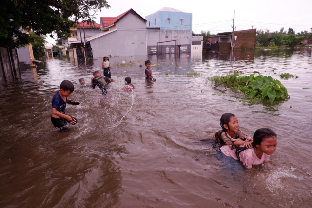 Sejumlah anak bermain di tengah banjir Perumnas Antang Blok 10, Makassar, Sulawesi Selatan, Kamis (18/1/2024).