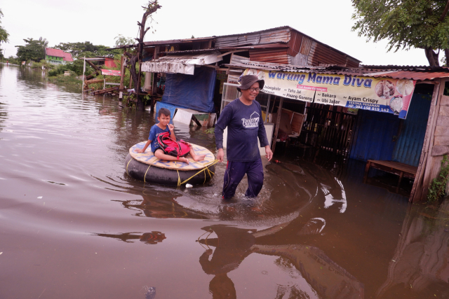 Warga menerobos banjir yang merendam Kompleks Perumnas Antang Blok 10, Makassar, Sulawesi Selatan, Kamis (18/1/2024).