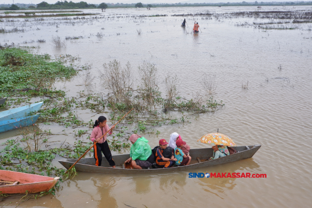 Sejumlah pelajar pulang dari sekolah menggunakan sampan melintasi area persawahan yang terendam banjir di Romang Tangngaya, Manggala, Makassar, Sulawesi Selatan.