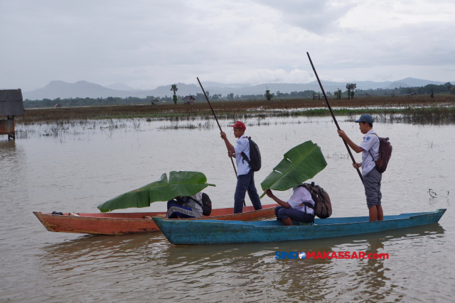 Sejumlah pelajar pulang dari sekolah menggunakan sampan melintasi area persawahan yang terendam banjir di Romang Tangngaya, Manggala, Makassar, Sulawesi Selatan.