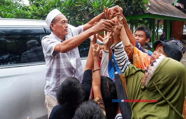 Pengunjung membagikan sedekah kepada tukang bersih-bersih kubur di Tempat Pemakaman Umum (TPU)Panaikang, Makassar, Kamis (7/3/2024).