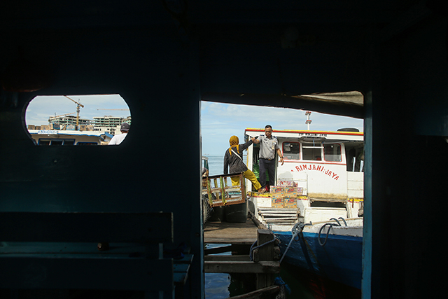 Petugas Dinas Perhubungan membantu warga untuk naik ke atas perahu di Dermaga Kayu Bangkoa, Selasa (30/1/2024).