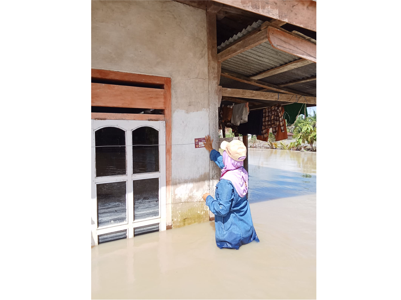 Petugas Pantarlih menempelkan stiker di rumah warga saat sedang banjir di Baebunta Selatan, Kabupaten Luwu Utara. Dok KPU Luwu Utara