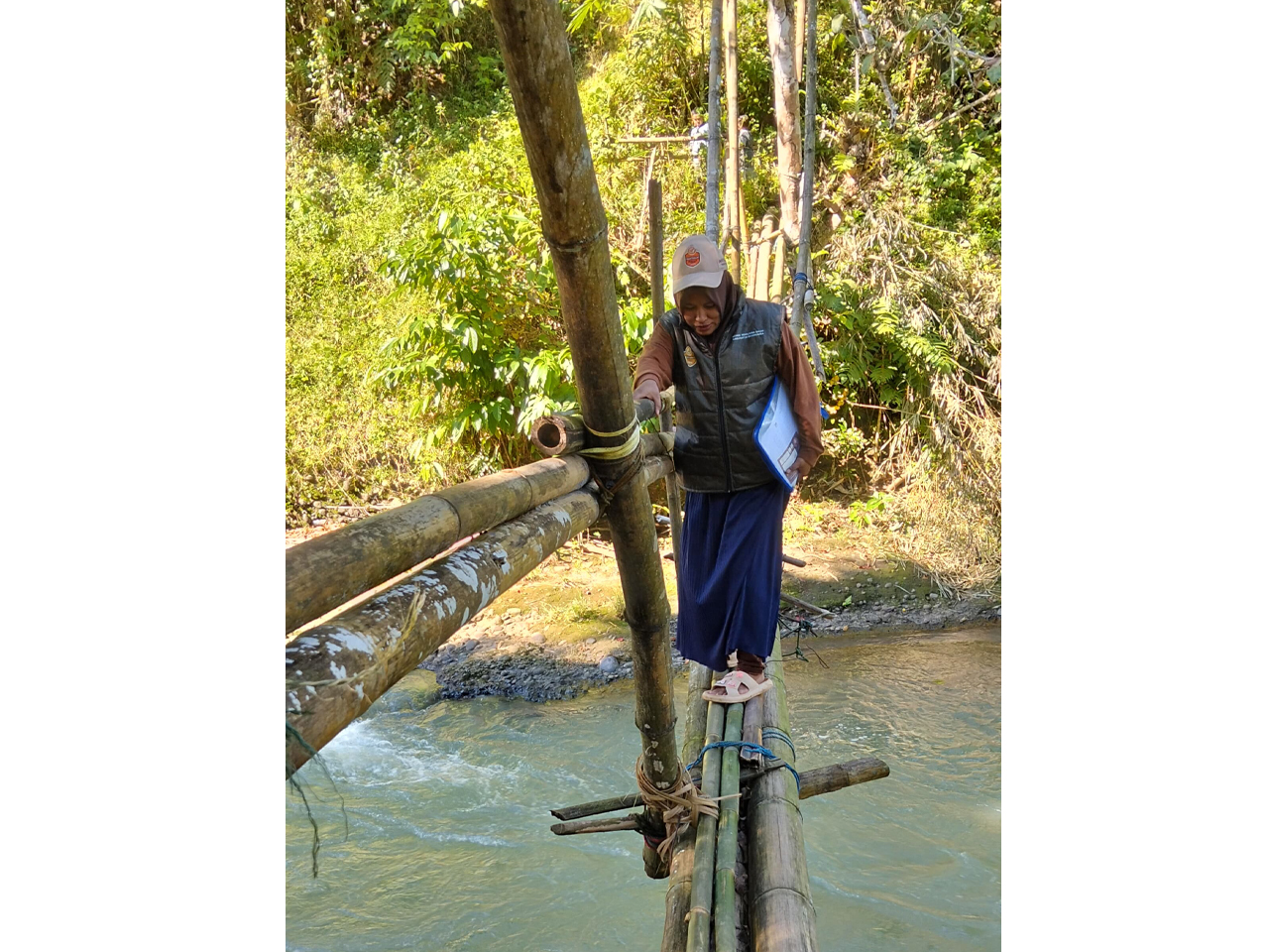 Petugas Pantarlih, Juliana menyeberangi sungai dengan melewati jembatan bambu untuk melakukan Coklit untuk TPS 3 Dusun Sapanang, Desa Sapanang, Kecamatan Kajang, Kabupaten Bulukumba. Dok KPU Bulukumba