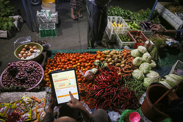 Pedagang pasar mengkases aplikasi mobile banking D-Bank PRO di Makassar, Jumat (23/8/2024).