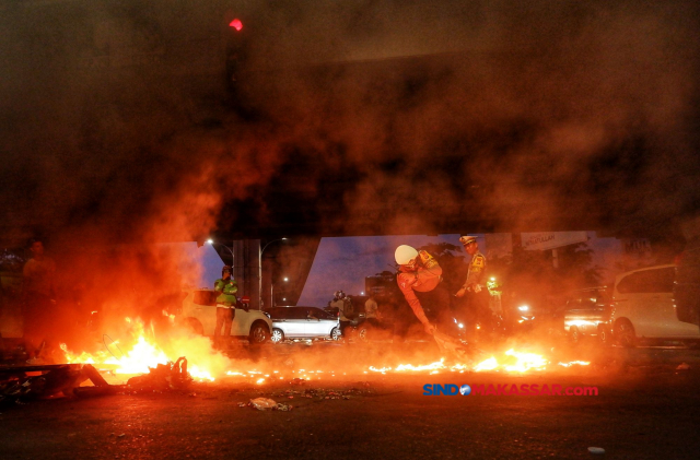 Polisi berusaha memadamka api yang dibakar pengunjuk rasa di bawah jembatan layang Makassar, Sulawesi Selatan, Senin (26/8/2024).