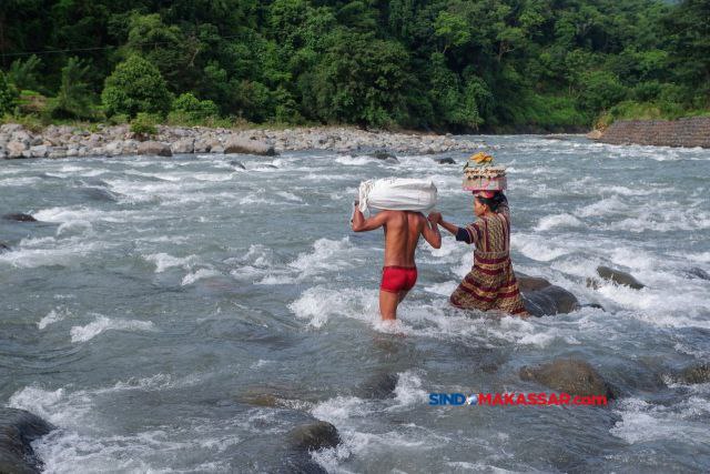 Warga membawa telur dan ikan dari pasar saat melintasi derasnya arus sungai di Desa Bonto Matinggi, Kecamatan Tompobulu, Kabupaten Maros, Sulsel, Kamis (15/02/2024).