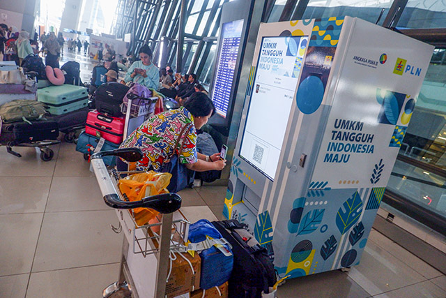 Penumpang bandara melakukan transaksi pembelian produk Usaha Mikro Kecil Menengah (UMKM) di vending machine Bandara Internasional Soekarno-Hatta, Kamis (27/6/2024).