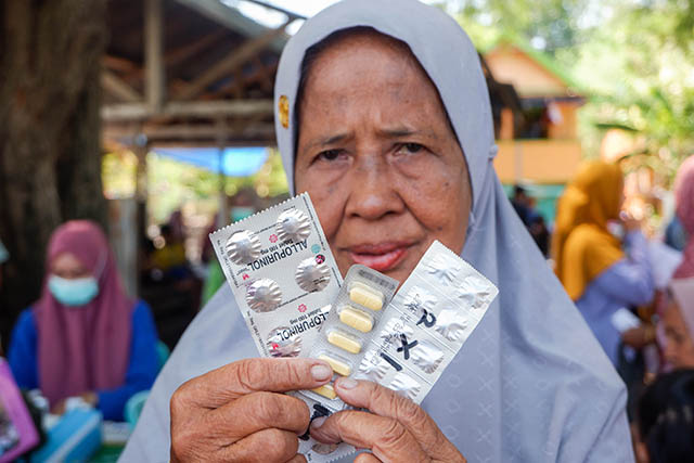 Warga memperlihatkan obat yang diberikan usai melakukan pemeriksaan kesehatan secara gratis.