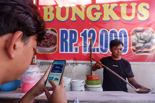 Pemilik warung coto mengakses aplikasi ICONNET di Warung Coto Makassar.