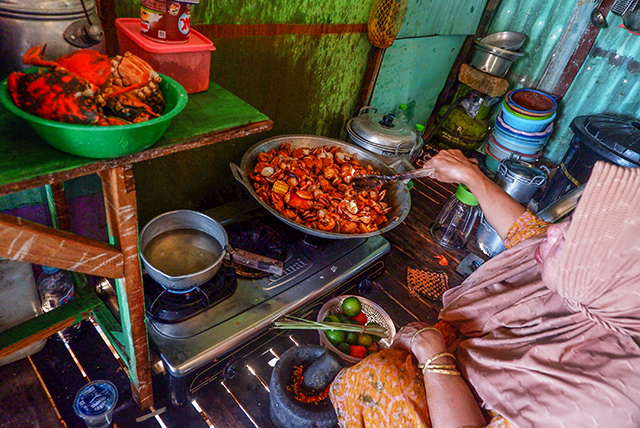 Warga memasak kepiting hasil tangkapan nelayan di peisir Kampung Lantebung, Kecamatan Biringkanaya, Makassar, Minggu (18/8/2024).