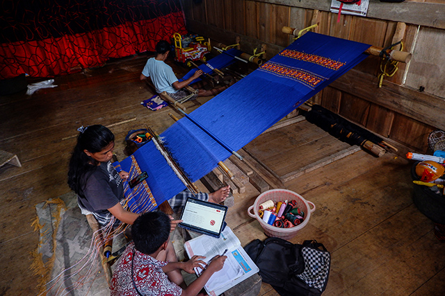 Seorang penenun bersama anaknya mengakses secara online Sekolah Pasar Modal di Dusun Lembang, Desa Sa'dan Andulan, Kecamatan Sa'dang, Toraja Utara.