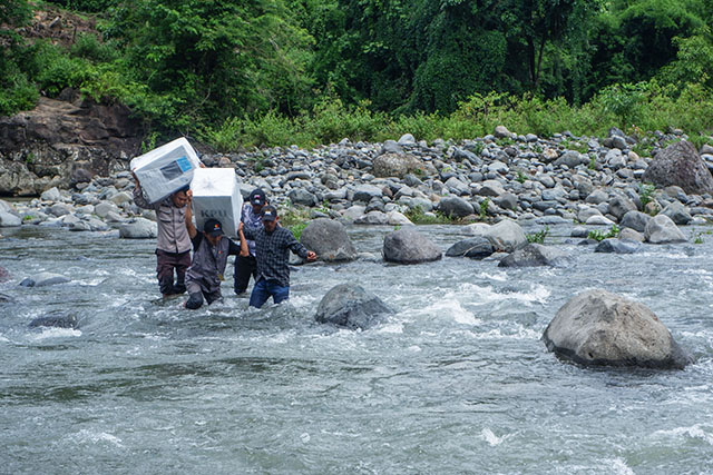 Personel kepolisian bersama petugas Bawaslu menyeberangi Sungai Tompobulu untuk mendistribusikan logistik Pilkada 2024 ke Dusun Makmur, Desa Bonto Manurung, Kecamatan Tompobulu, Kabupaten Maros.