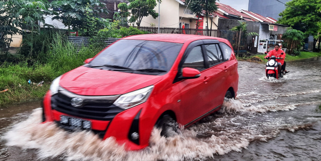 Pengendara melintasi banjir di Jalan Kecaping Raya, Perumnas Antang Blok 10, Makassar.