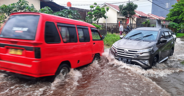 Pengendara melintasi banjir di Jalan Kecaping Raya, Perumnas Antang Blok 10, Makassar.