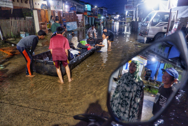 Warga menggunakan perahu di Jalan Nipa-nipa, Kecamatan Manggala, Makassar, Minggu (22/12/2024).