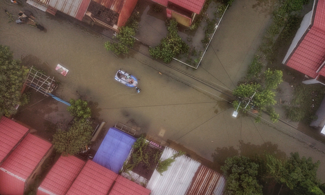 Warga menggunakan perahu di Blok 10, Perumnas Antang, Kecamatan Manggala, Makassar, Minggu (22/12/2024).