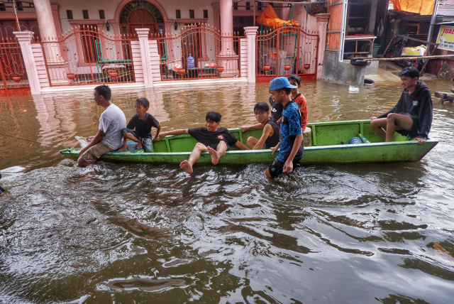 Warga menggunakan perahu di Jalan Nipa-nipa, Kecamatan Manggala, Makassar, Minggu (22/12/2024).