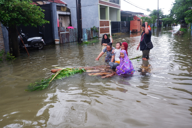 Warga bermain di tengah banjir di Blok 10, Perumnas Antang, Makassar, Makassar, Minggu (22/12/2024).